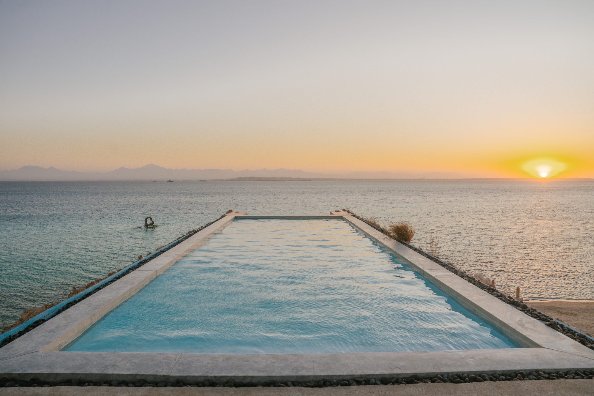 The Ozirea Infinity Pool suspended between sea and sky at sunset